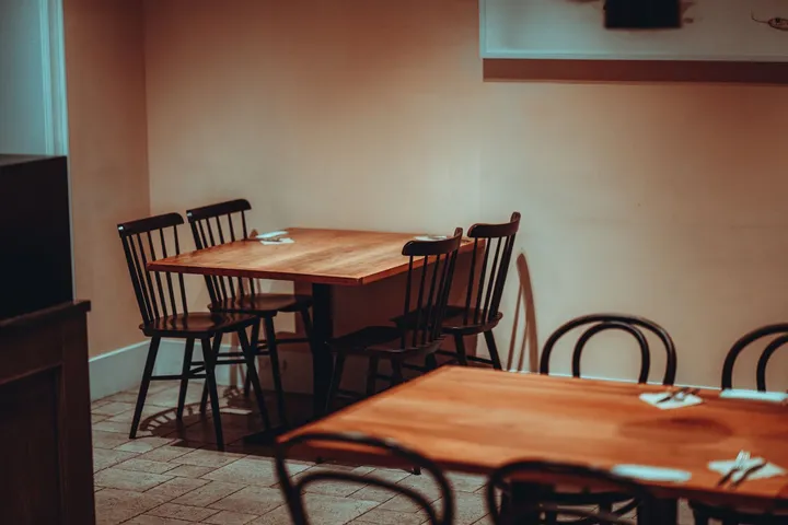 분홍빛 벽 앞에 놓인 원목 테이블과 의자