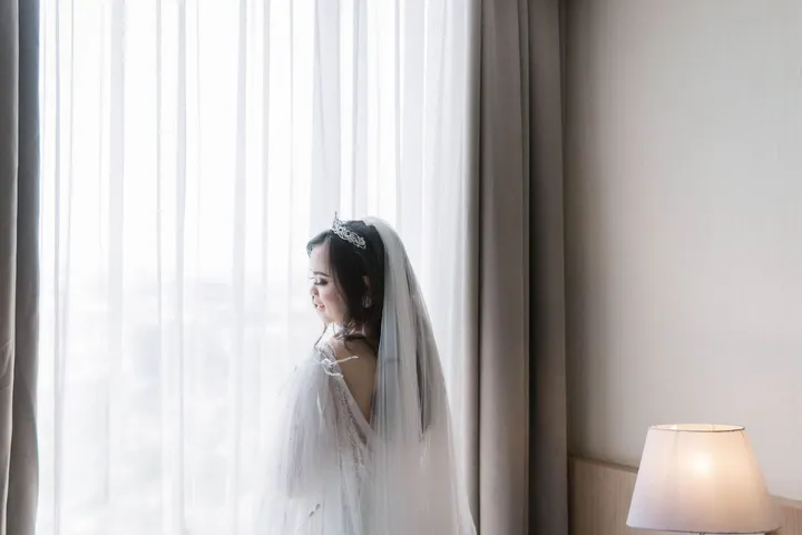 창가의 커튼 빛 속에 선 신부
