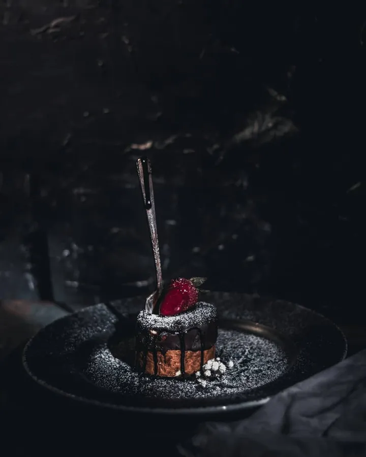 검은 접시 위의 딸기를 얹은 초콜릿 디저트
